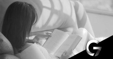 Imagem de uma mulher lendo um livro deitada no sofá